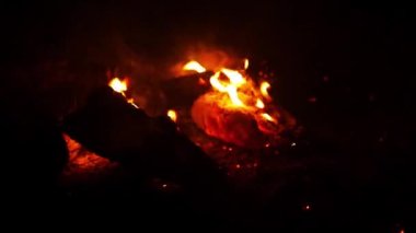 Gece kamp ateşine yakın, yanan odunlar ve uçan alev kıvılcımlarıyla