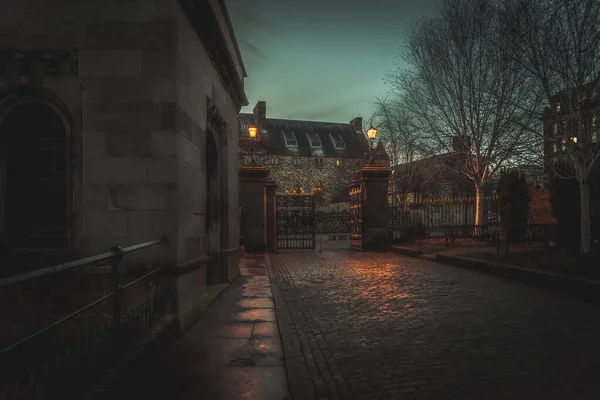GLASGOW, SCOTLAND, 16 DE DICIEMBRE DE 2018: Espeluznante calle adoquinada rodeada de antiguos edificios de estilo europeo. Iluminado solo con luz débil de farolas. — Foto de Stock