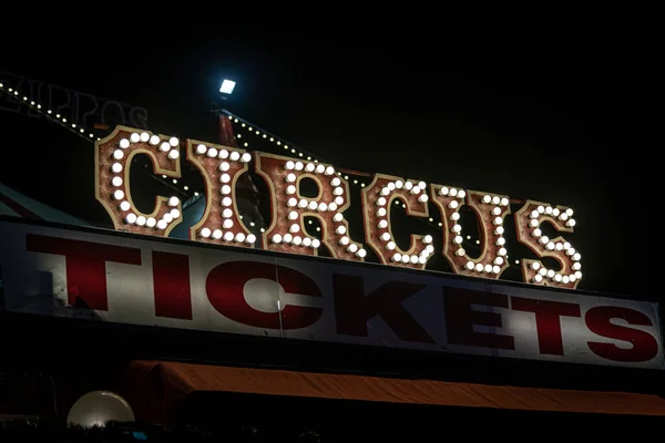 Antiguo letrero de circo débilmente iluminado con bombillas en la oscuridad sobre un puesto de venta de entradas. Típica vista de una entrada a un circo. Concepto de diversión, familia y alegría. Fotos De Stock