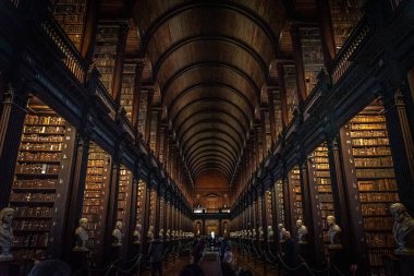 DUBLIN, IRELAND, 21 ARALIK 2018: The Long Room in the Trinity College Library, home of Kells. Büyük miktarda kitap ve sandık heykeliyle mekânın perspektifi.