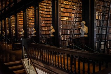 DUBLIN, IRELAND, 21 ARALIK 2018: The Long Room in the Trinity College Library, home of Kells. Büyük miktarda kitap ve sandık heykeliyle mekânın perspektifi.