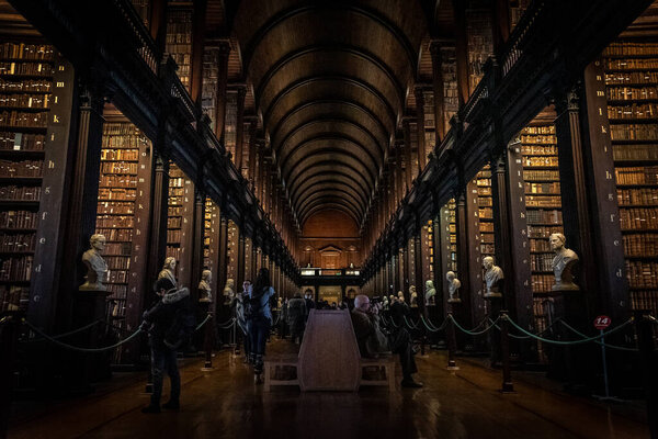 DUBLIN, IRELAND, DECEMBER 21, 2018: The Long Room in the Trinity College Library, home to The Book of Kells. Perspective view of the place, with large quantity of books and chest statues.