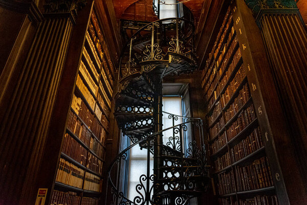 DUBLIN, IRELAND, DECEMBER 21, 2018: Magnificent spiral staircase in The Long Room in the Trinity College Library, home to The Book of Kells, full of details and ornamented.