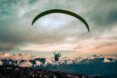Arjantin 'deki Bariloche Dağları' nın üzerinde, arka planda karlı zirvelerle yamaç paraşütü. Özgürlük kavramı, macera, uçmak.