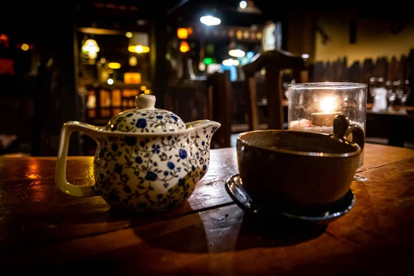 居心地の良いアイルランドのパブの木製のテーブルの上にガラスの中にティーポット、カップ、ティーライト — ストック写真