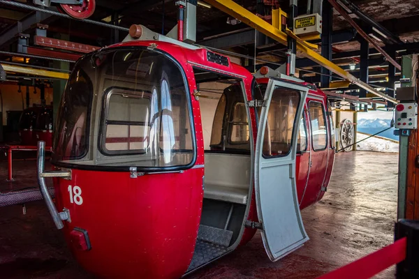 BARILOCHE, ARGENTINA, JUNI 19, 2019: Open rode kabelbaan wachtend op passagiers om naar de top van besneeuwde bergen te gaan gezien op de achtergrond. Vertaling "controleer deur slot" in het Spaans. — Stockfoto