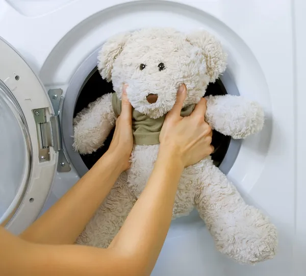 Mulher carregando brinquedo fofo na máquina de lavar roupa — Fotografia de Stock