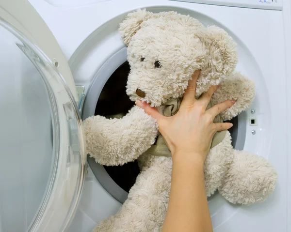 Жінка завантажує іграшку в пральну машину — стокове фото