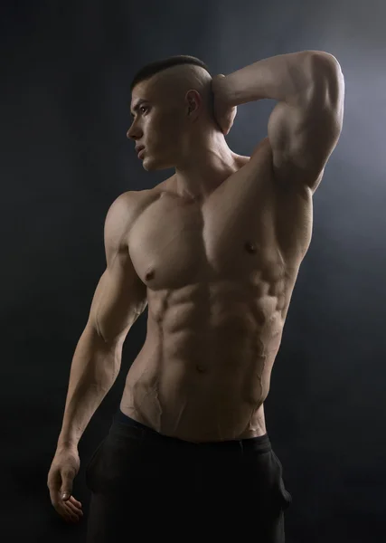 Молодий сексуальний чоловік зі спортивним тілом позує на чорному тлі . — стокове фото
