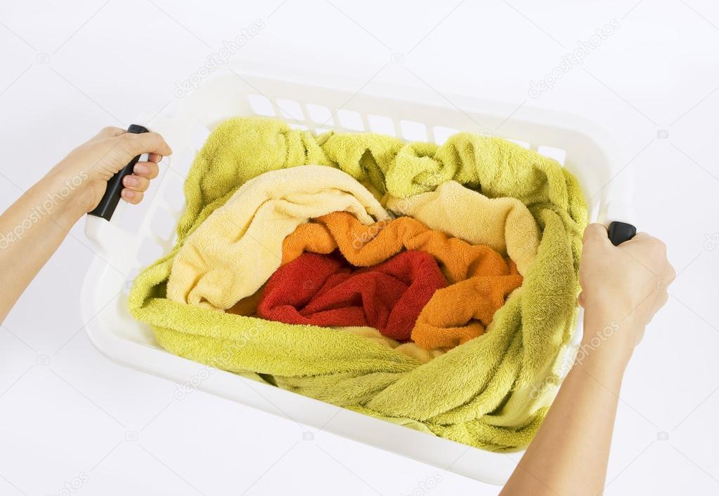 woman holding a basket with color laundry to wash