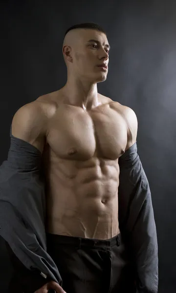 Young sexy man with athletic body on black background. — Zdjęcie stockowe