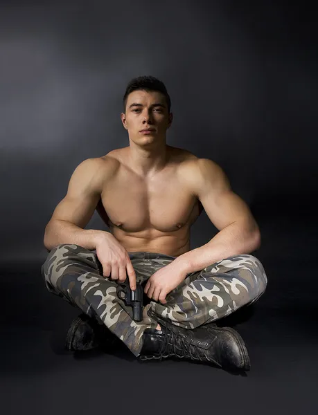 Young sexy man with athletic body in camouflage with gun — Stock Photo, Image