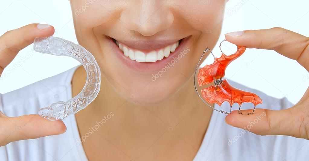 hands holding retainer for teeth and tooth tray