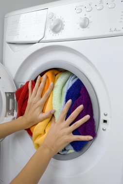 woman loading laundry in the washing machine clipart
