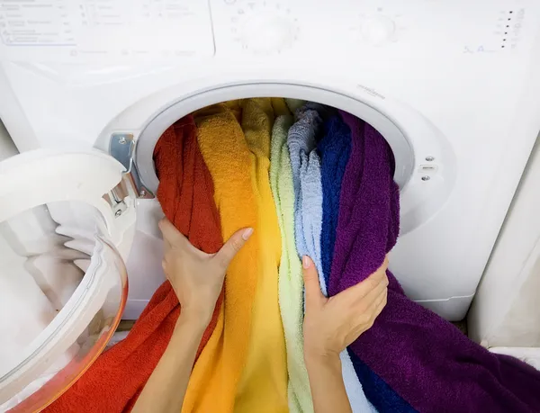 Woman taking color laundry from washing machine — Stock Photo, Image