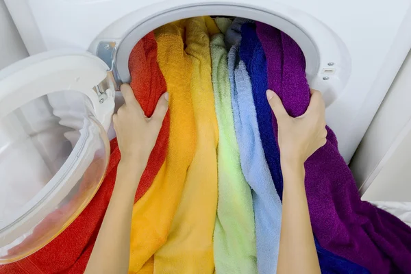 Mulher tomando roupas coloridas da máquina de lavar roupa — Fotografia de Stock