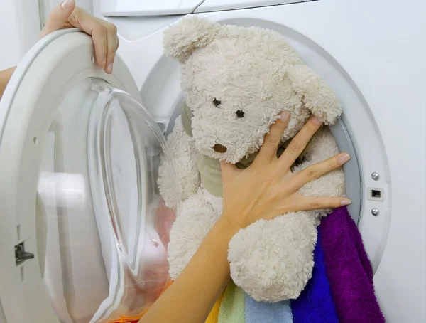 Woman loading fluffy toy in the washing machine — Stock Photo, Image