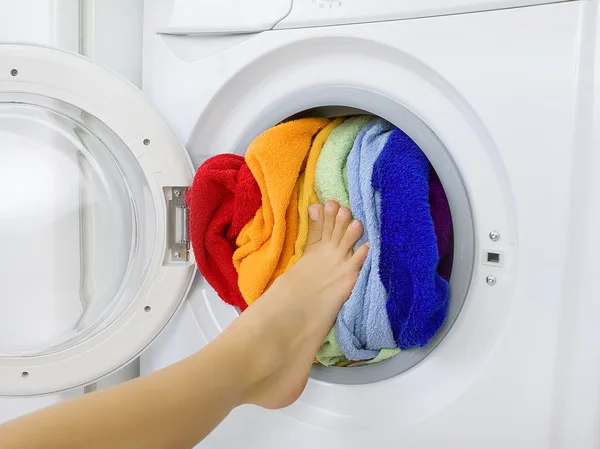 Жінка завантажує барвисту білизну в пральну машину — стокове фото