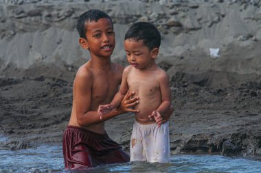 Kardeşini taşımak, nehirde yıkanmak, Yogyakarta, Endonezya. 23 Temmuz 2021