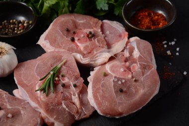 Baharat ve otlarla dolu bir masada çiğ ossobuco eti. İtalyan güveci için gerekenler