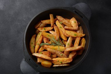 Fırında, baharatlı ve biberiyeli kızarmış patates dilimleri.