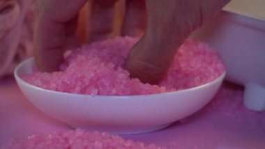 Elle oynanan pembe tuz kristalleri. Kaplıca banyosu için ölü deniz tuzu
