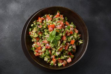 Domatesli Shirazi Salatası, salatalık, kırmızı soğan, maydanoz ve siyah kasede taze limon suyu. Persian Shirazi sebze salatası yakın plan. Popüler İsrail yemekleri