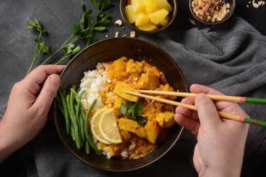 Arka planda siyah kâse içinde tavuk masajcısı körisi. Massaman köri, Tayland 'ın en iyi yemeği. Tavuk eti, patates, soğan ve birçok baharat Malay ve Tayland Müslüman kültürlerinden etkileniyor..