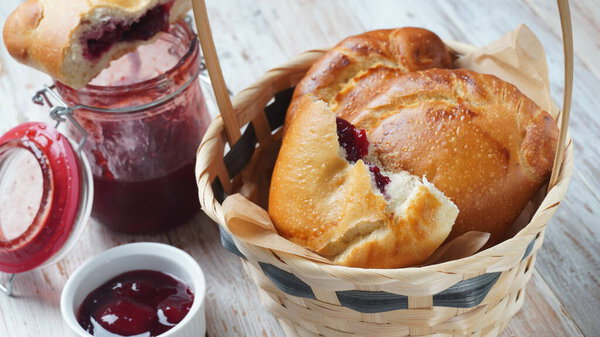 Вишневые пироги с ягодами вишни, миска с вишневым джемом. Домашние сладкие пироги из дрожжевого теста, свежеиспеченного в духовке