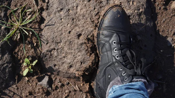 Women boots in the mud, detail of dirty boots and muddy, walk. Top down dirty black laced boots woman in blue jeans.