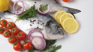 Çiğ çiğ çiğ dorado veya limonlu çipura balığı, otlar, vişneli domates ve siyah arka planda baharatlar.