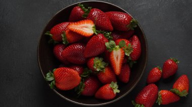 Tabakta çilekli taze organik meyve. Yapraklı çilek. Siyah bir arkaplanda izole edilmiş.