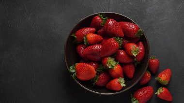 Tabakta çilekli taze organik meyve. Yapraklı çilek. Siyah bir arkaplanda izole edilmiş.