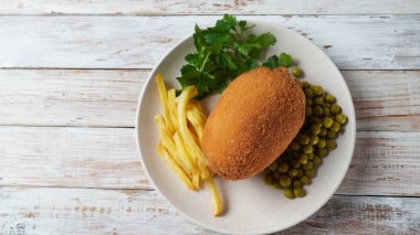 Tavuk Kiev, Ukrayna mutfağı. Tereyağı ve otla doldurulmuş ekmek kırıntıları içinde tavuk pirzolası, yeşil bezelye ve patates cipsi ile servis edilir.
