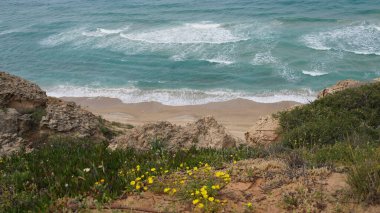 Yazın güzel deniz kıyısı. Sakin mavi deniz manzarası. Taşlı ve kumlu deniz kıyısı. Güneşli deniz manzarası. Netanya Şehri, İsrail