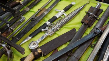 Bıçaklar, tıkırtılar, soğan, dirk, poniard, snickersnee, stiletto ve masadaki diğer eski ve modern soğuk silahlar.