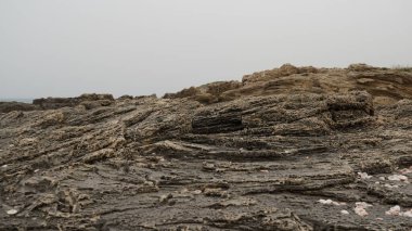 Deniz kıyısındaki volkanik kaya levhaları. Deniz kıyısındaki doğal kayalık dalgalı su