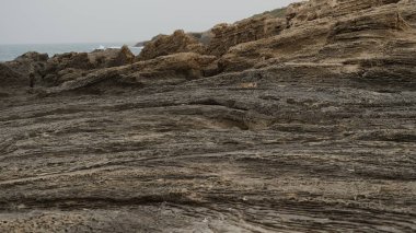 Deniz kıyısındaki volkanik kaya levhaları. Deniz kıyısındaki doğal kayalık dalgalı su