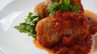 Doldurulmuş lahana ruloları, domates sosu ve bitkilerle.