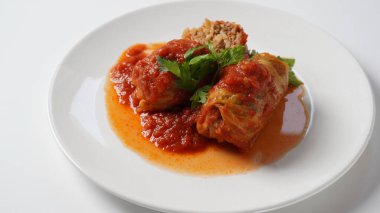 Doldurulmuş lahana ruloları, domates sosu ve bitkilerle.