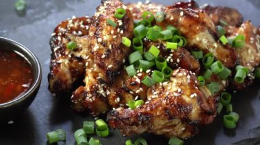 Kızarmış iştah açıcı tavuk kanatları yeşil soğanla süslenmiş.