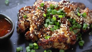 Kadının eli bir parça kızarmış iştah açıcı kızarmış tavuk kanadı alıyor yeşil soğanla süsleniyor.