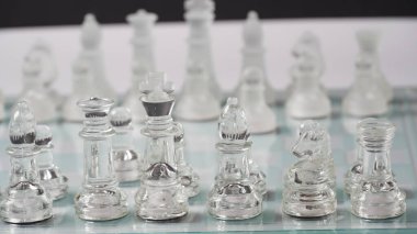 Transparent chess figures, on starting position, on reflective chess board. Chess board game