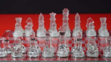 Transparent chess figures, on starting position, on reflective chess board, red tone. Strategic Chess board game
