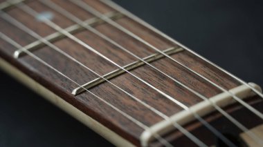 Guitar neck of black electric guitar on dark background