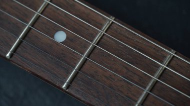 Guitar neck of black electric guitar on dark background