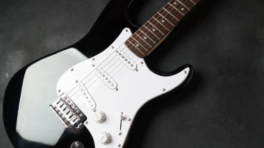 Front of electric guitar body on dark background.