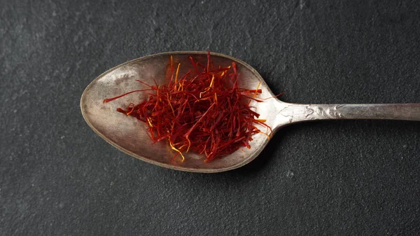 Expensive Red Dried saffron spice in a spoon on dark background