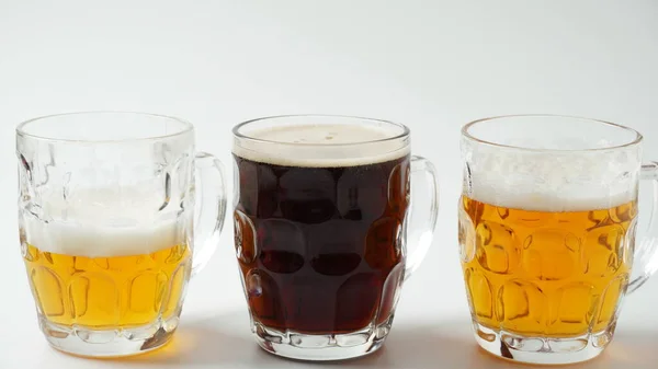 Three mugs of beer different flavor - light, dark, and red