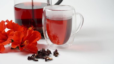 Şeffaf bir bardak ve sıcak kırmızı çiçek çayı.